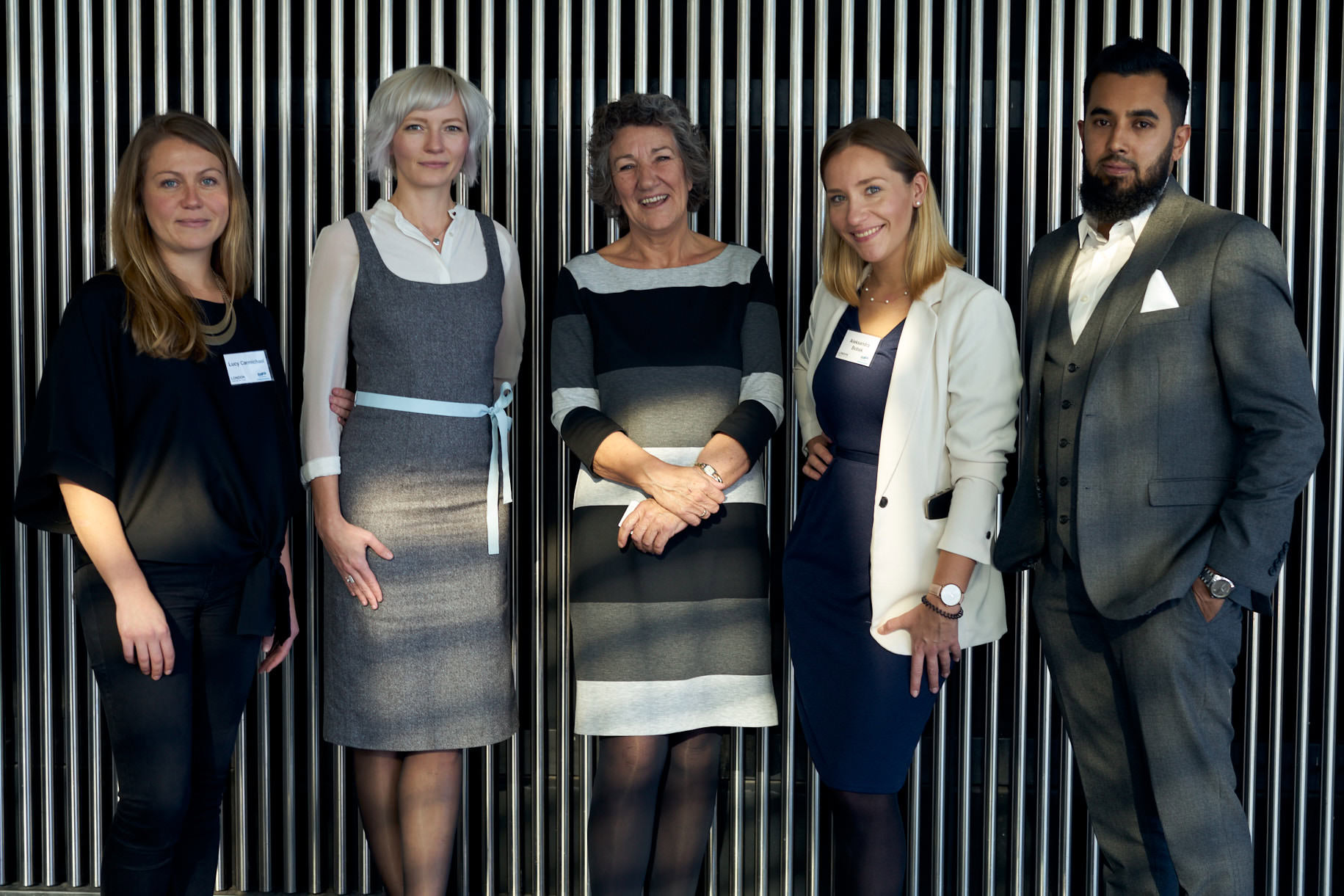 Five professionals standing together for a group photograph in a formal setting.