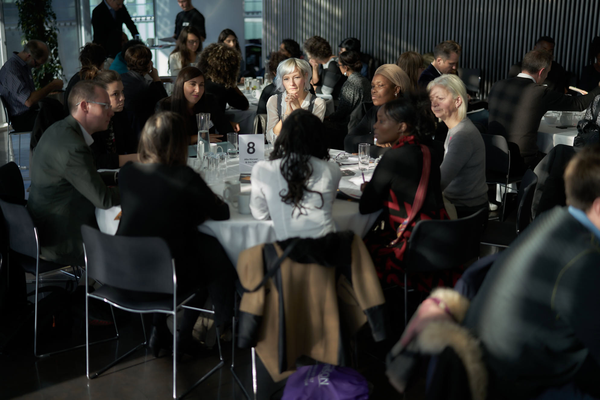 A diverse group of people engaged in discussion around a round table during an event.