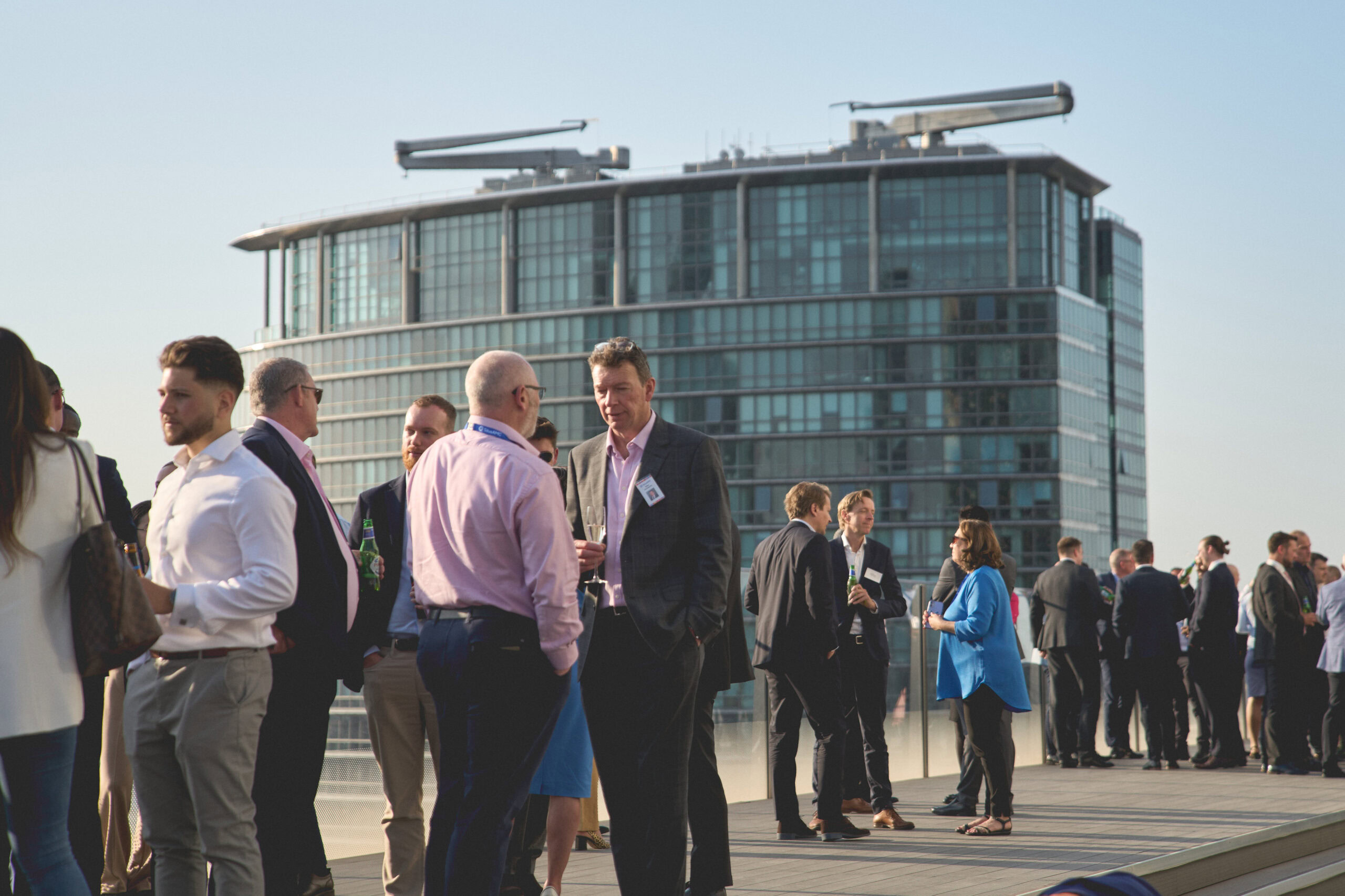 Group of professionals networking on a rooftop with a modern building in the background.