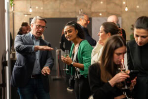 People engaged in conversation and drinking at a warmly lit social gathering.