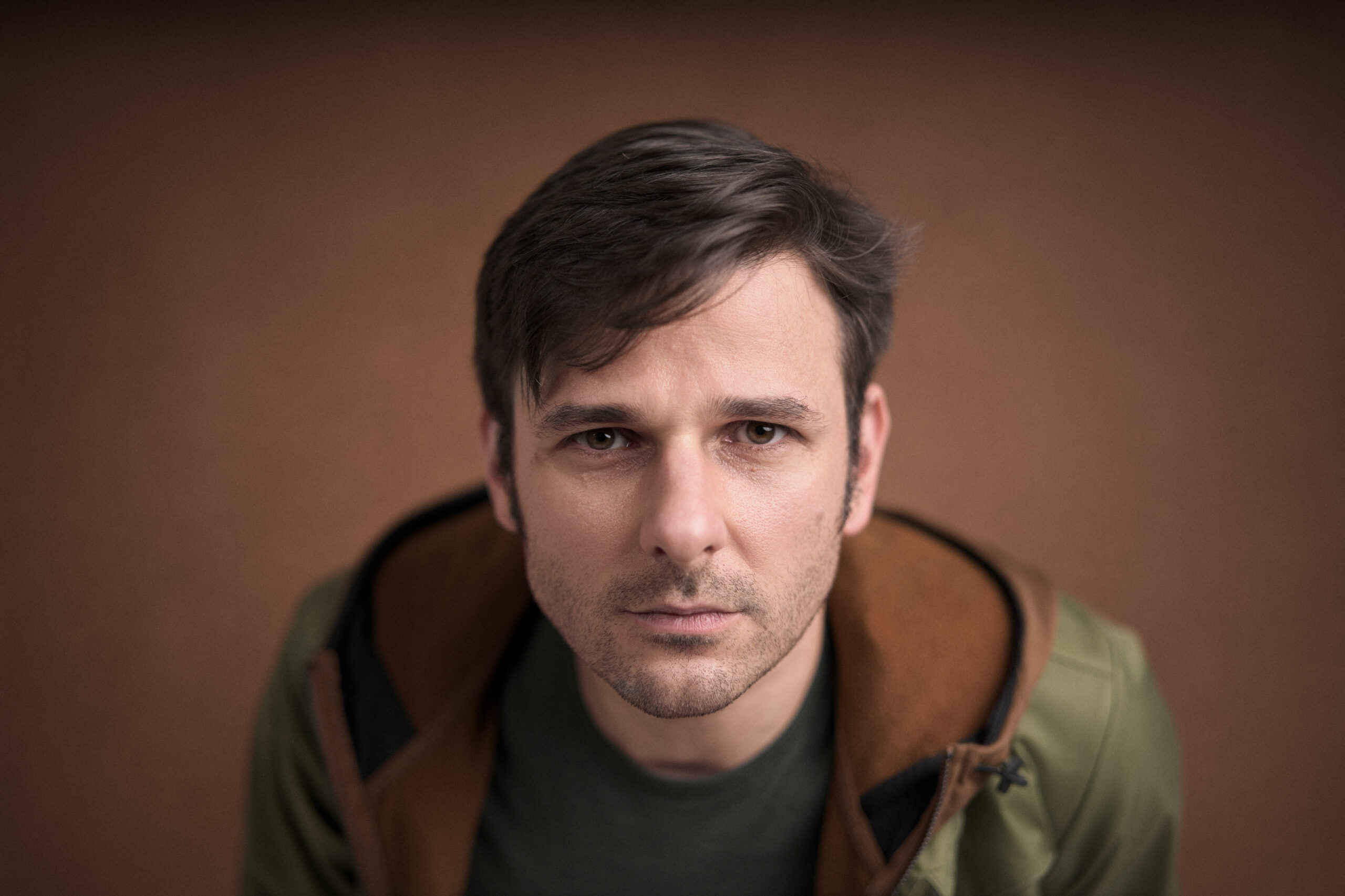 Adam Toth, London Headshot Photographer Feel Confident and Look Authentic in Your Photos - Portrait of an individual in a natural pose with a neutral expression, captured in a warm-toned setting. The lighting is soft and subtle, creating an intimate and approachable mood. This example of portrait photography by Adam Toth showcases Tadam Photography's expertise in creating authentic expressions in London settings, a specialty of the photographer.