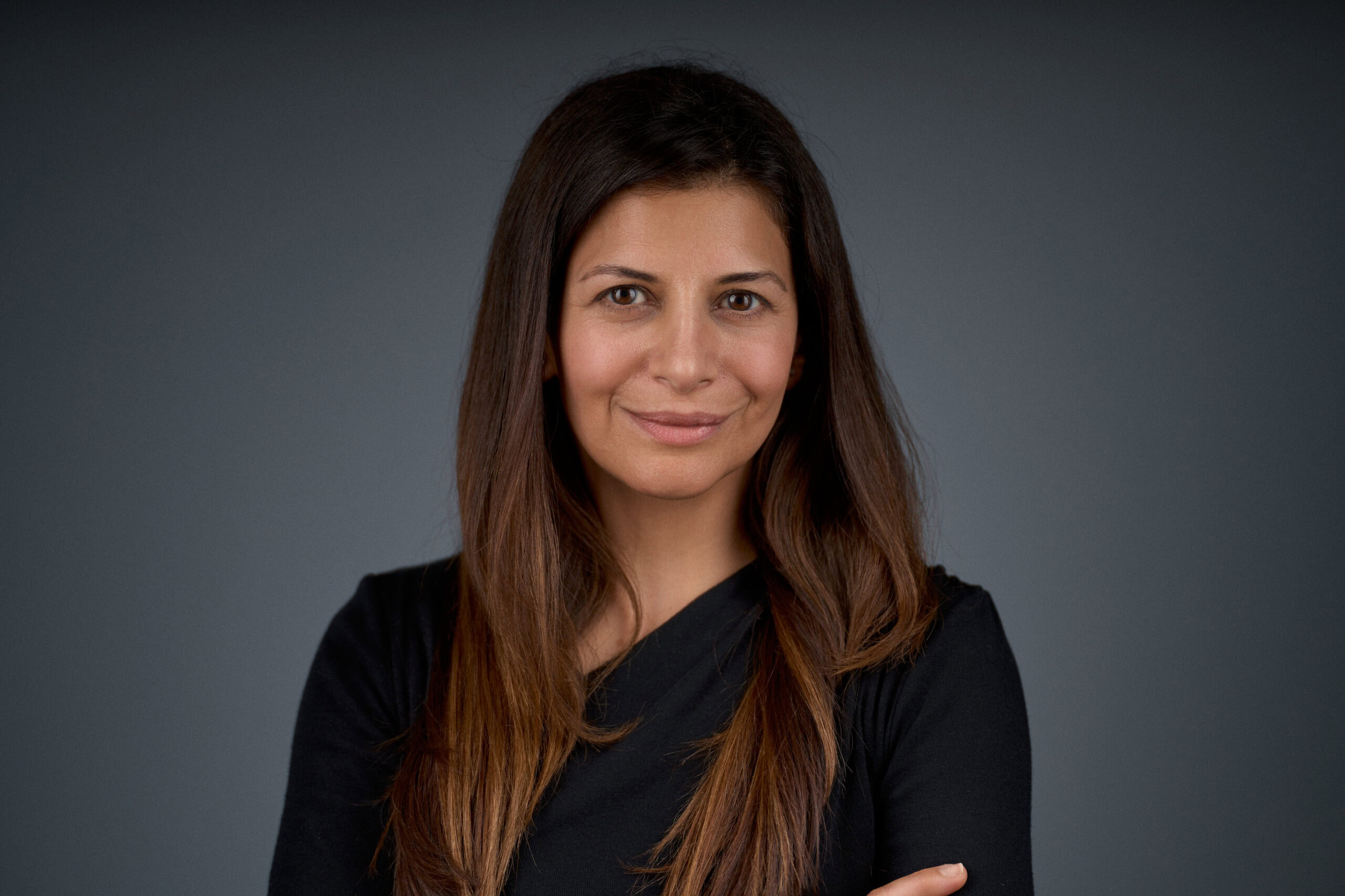 Corporate headshot by Adam Toth of Tadam Photography, featuring a woman with long brown hair and a confident expression in a natural pose. The setup includes professional studio lighting and a clean, neutral background, creating a polished and professional mood. Captured in London, this image highlights Toth's expertise in delivering high-quality portrait photography.